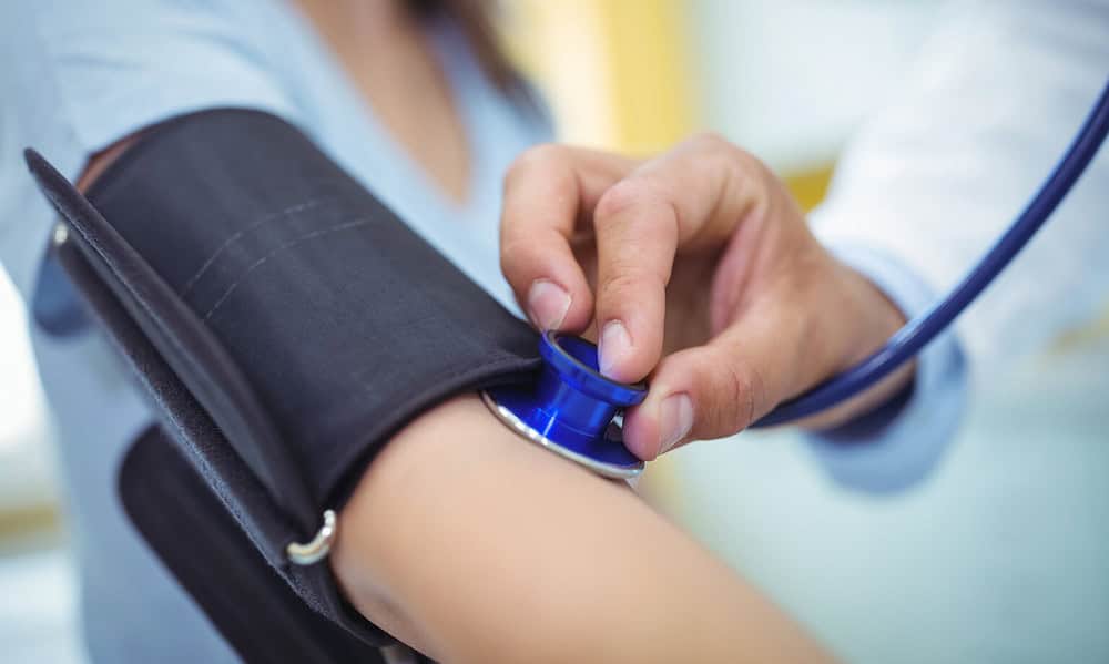 Doctor checking female patient blood pressure in the hospital