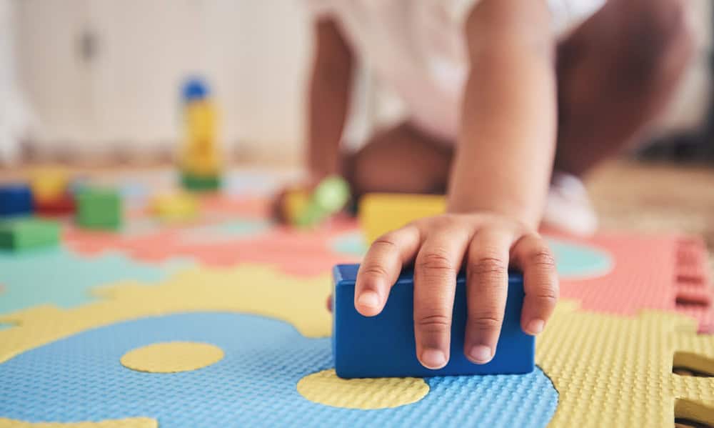 Building blocks, hands and toddler at daycare with development on number carpet and ground. Learning, baby and toy with nursery, motor skills and child game at kindergarten with youth and cube Building blocks, hands and toddler at daycare with development on number carpet and ground. Learning, baby and toy with nursery, motor skills and child game at kindergarten with youth and cube.