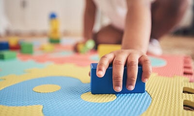 Building blocks, hands and toddler at daycare with development on number carpet and ground. Learning, baby and toy with nursery, motor skills and child game at kindergarten with youth and cube Building blocks, hands and toddler at daycare with development on number carpet and ground. Learning, baby and toy with nursery, motor skills and child game at kindergarten with youth and cube.