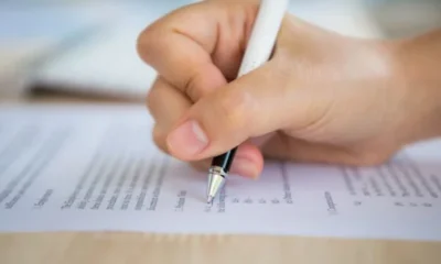 Imagem mostra uma mão segurando uma caneta sobre um papel, ilustrando o concurso público - Freepik