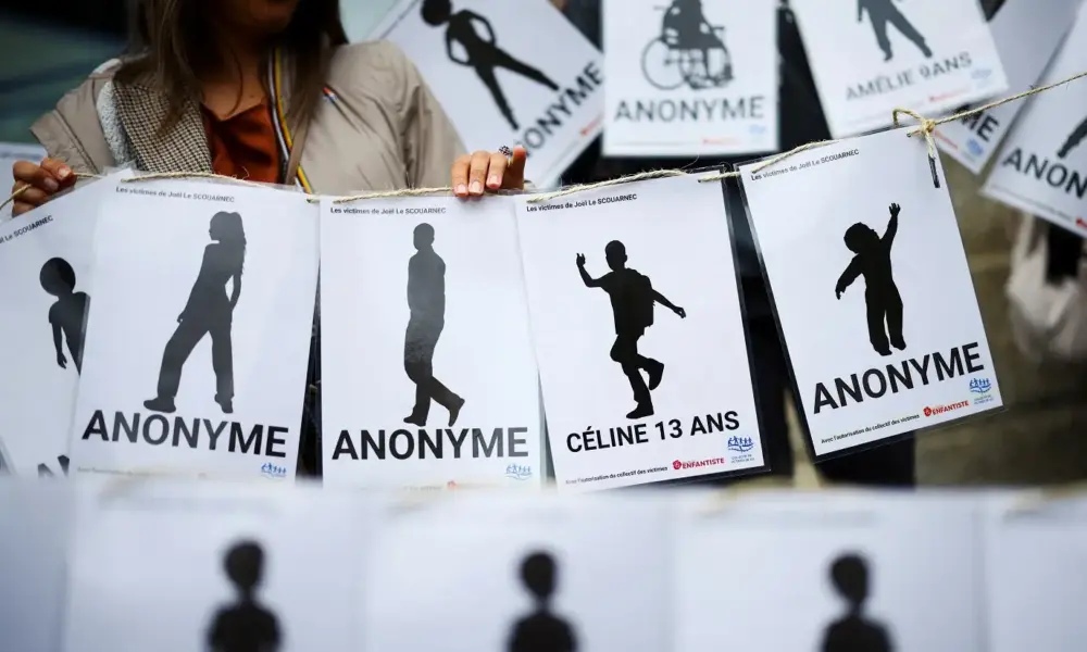 Uma pessoa segura cartazes enquanto um grupo de supostas vítimas, membros de coletivos femininos, ONGs e sindicatos se reúne em frente ao tribunal no dia do veredicto do ex-cirurgião Joel Le Scouarnec, acusado de estupro agravado e abuso sexual contra centenas de crianças ao longo de várias décadas, no tribunal de Vannes, Bretanha, França, 28 de maio de 2025. REUTERS/Stephane Mahe TPX IMAGENS DO DIA